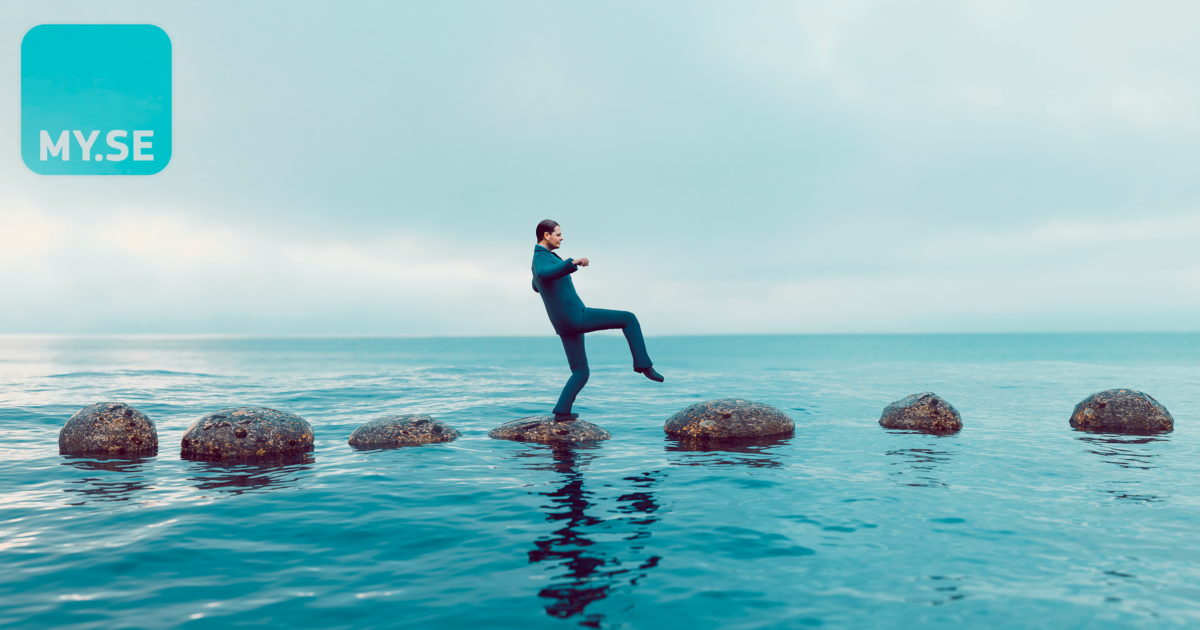 En person i kostym går försiktigt på runda stenar över vatten under en molnig himmel. MY.SE-logotypen syns i det övre vänstra hörnet.