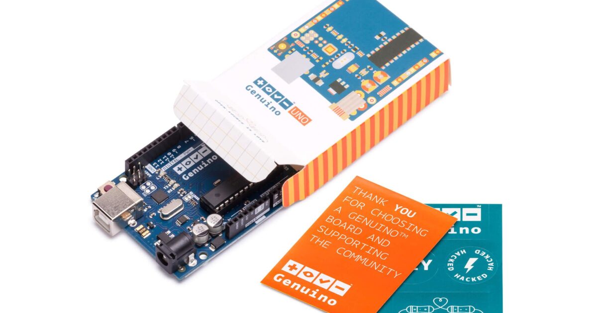 Ett Arduino-elektronikkort delvis ur sin färgglada låda, med ett tackkort och en grön klistermärke bredvid, allt märkt Genuino.
