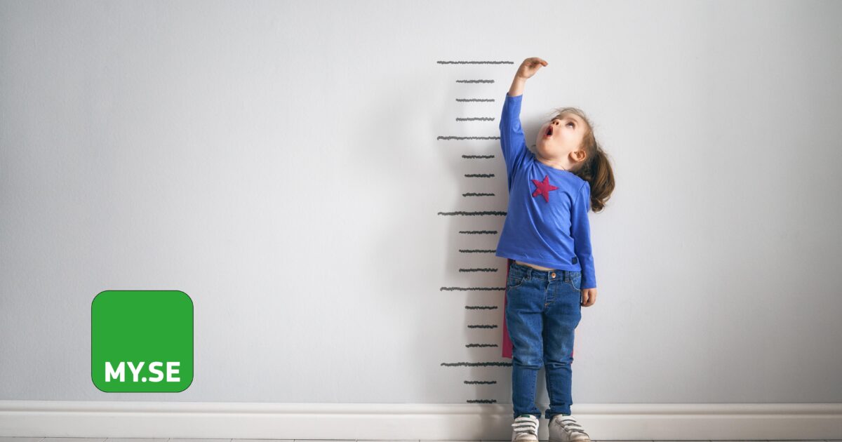En ung flicka står mot en vägg med höjdmarkeringar och sträcker sig uppåt med ett förvånat uttryck. Hon bär en blå skjorta med en röd stjärna och jeans. En grön fyrkant med MY.SE finns till vänster i bilden.