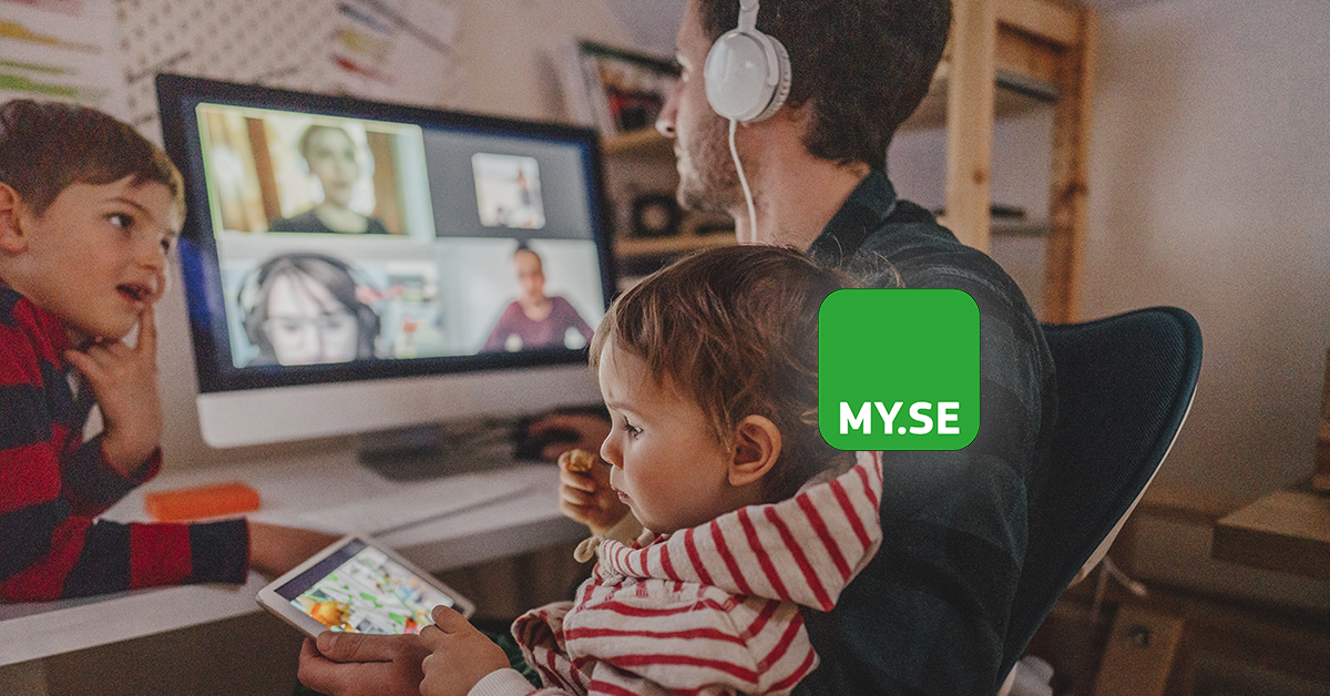 En man med hörlurar sitter vid ett skrivbord med ett litet barn i knät och håller en surfplatta. En ung pojke lutar sig mot skrivbordet. En datorskärm visar ett videosamtal med flera personer. MY.SE-logotypen är överlagrad.