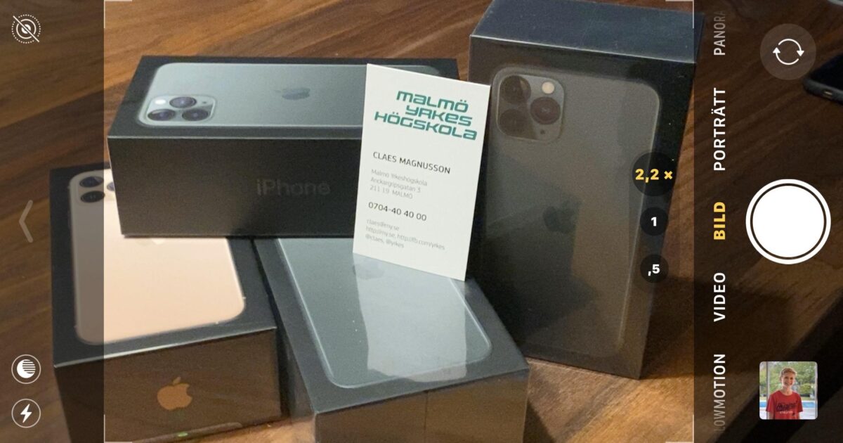 Flera iPhones i kartonger ligger placerade på en träyta. Ett visitkort från Malmö Yrkeshögskola ligger upprätt bland kartongerna. Bilden ser ut att ses genom ett telefonkameragränssnitt.
