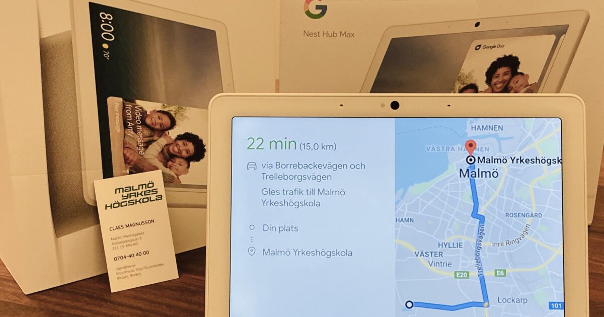 En Google Nest Hub Max som visar en navigeringsrutt till Malmö Yrkeshögskola sitter framför förpackningen. Ett visitkort för Malmö Yrkeshögskola placeras bredvid enheten.