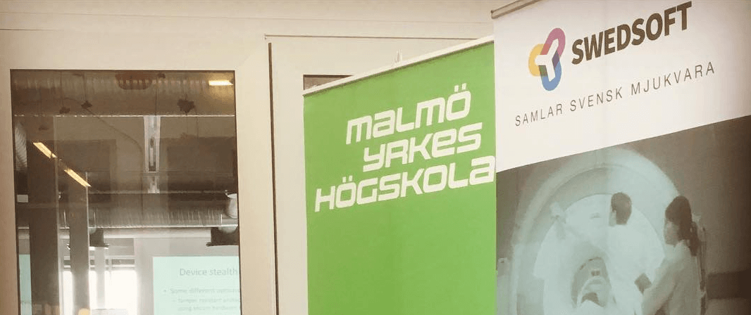 En grön banderoll med Malmö Yrkeshögskola och en Swedsoft banderoll med loggan och texten Samlar Svensk Mjukvara visas inomhus framför en glasvägg.