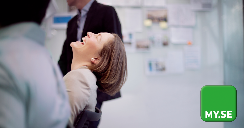 En kvinna sitter i en kontorsstol och skrattar glatt, med två suddiga kollegor i närheten. Bakgrunden är ljus och professionell, med MY.SE:s logotyp i nedre högra hörnet.