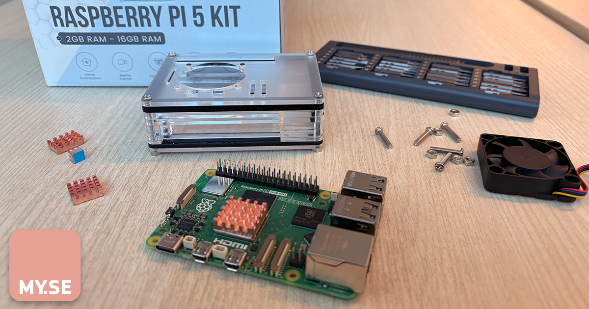 En Raspberry Pi 5-kit visas på en träyta med sina komponenter: ett huvudkretskort, kylflänsar, skruvar, en kylfläkt, ett plasthölje och en märkt låda i bakgrunden.