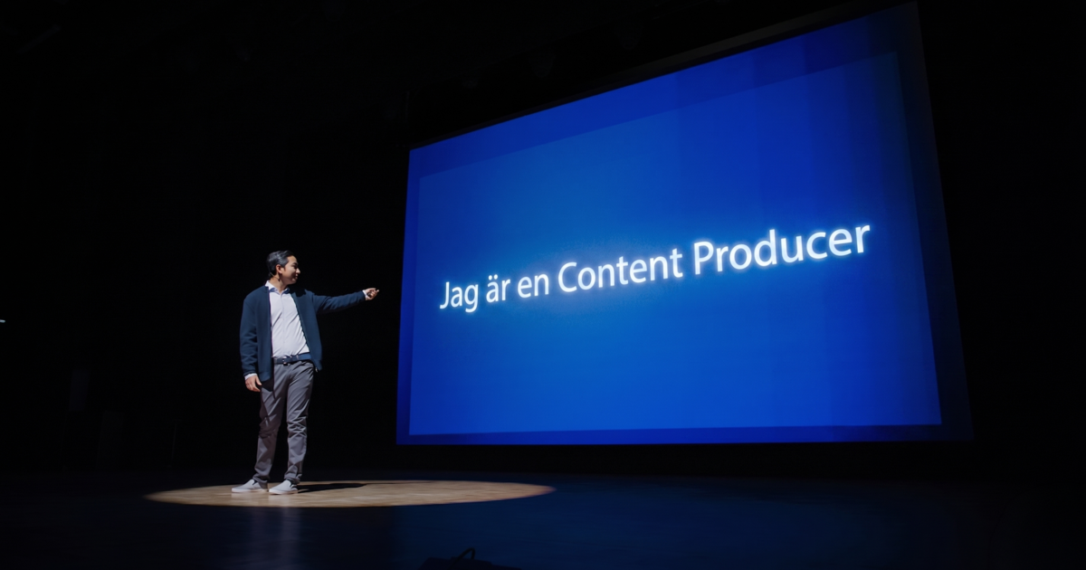 En man står på en scen i strålkastarljus och pekar på en stor blå skärm där det står Jag är en Content Producer, vilket betyder Jag är en innehållsproducent.